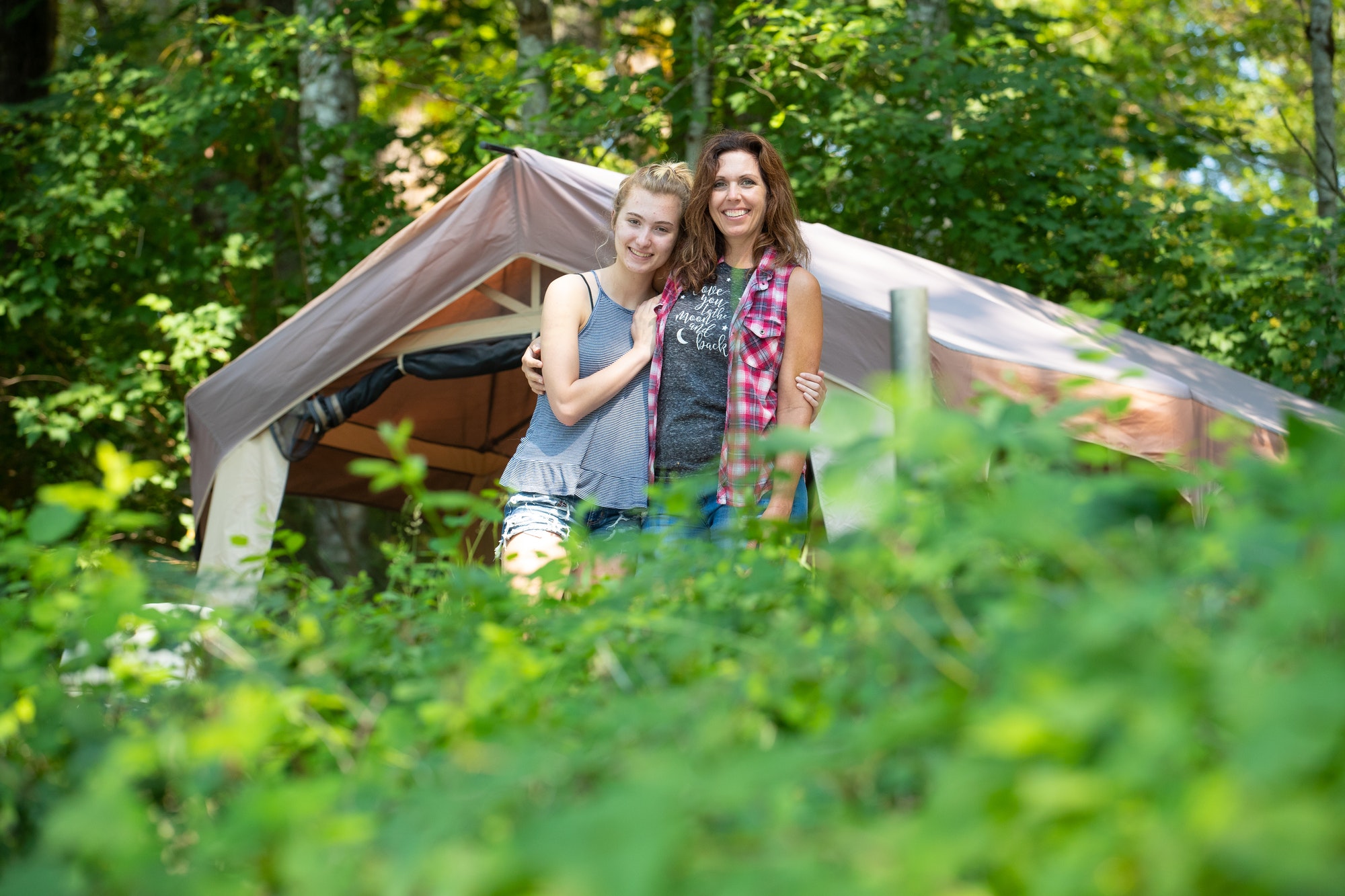 Happy mother and daughter camping in nature
